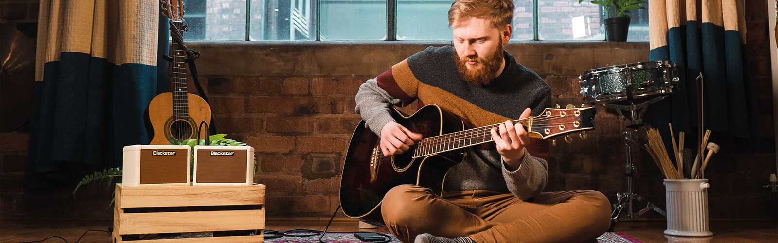 bearded man playing acoustic guitar that's connected to a blackstar guitar amp